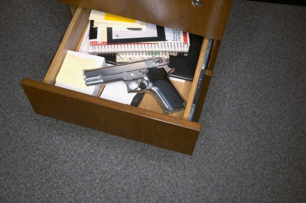 Pistol inside open desk drawer with documents.
